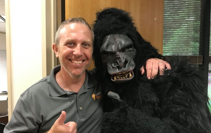 LeadsNearby President & co-founder Mark Sherwin smiling and posing with someone in a gorilla costume during a lighthearted, fun office moment, highlighting creativity and camaraderie.